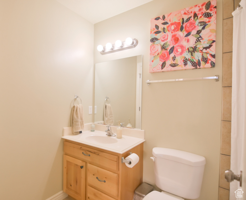Full bath featuring vanity, toilet, and baseboards
