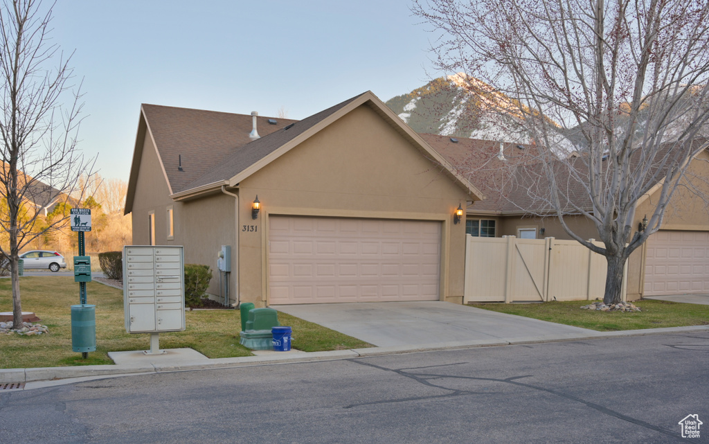 View of front of property featuring fence, stucco siding, driveway, a garage, and a mountain view