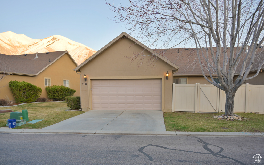 View of front of home with a front yard, fence, driveway, an attached garage, and stucco siding