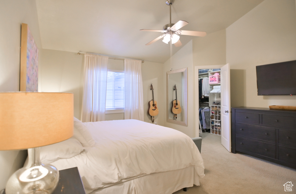 Bedroom with a walk in closet, light carpet, a ceiling fan, a closet, and vaulted ceiling