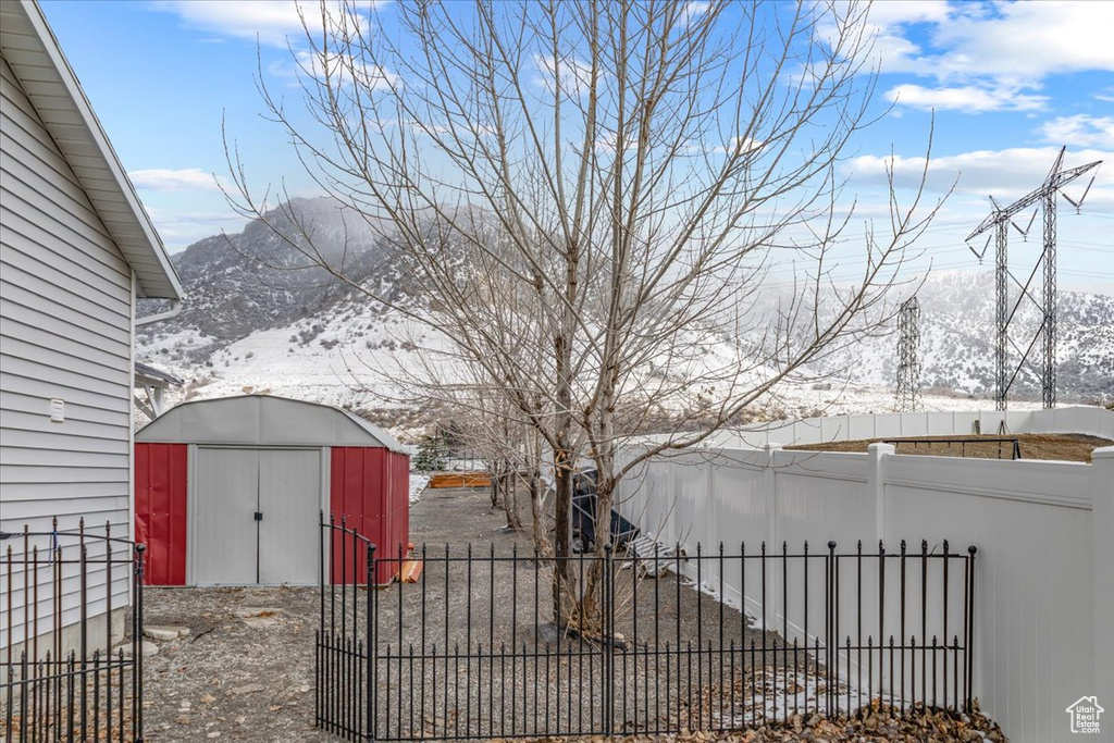 View of yard with an outbuilding, a shed, a mountain view, and fence private yard