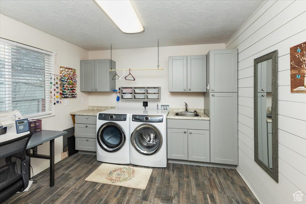 Clothes washing area with dark wood finished floors, separate washer and dryer, cabinet space, a sink, and a textured ceiling
