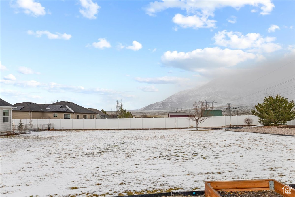Yard covered in snow featuring a mountain view and a fenced backyard
