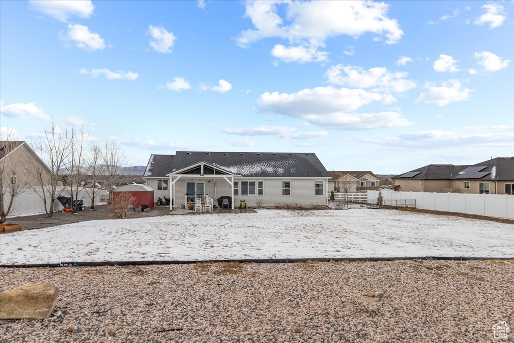 Snow covered back of property with a storage unit, an outbuilding, and fence private yard