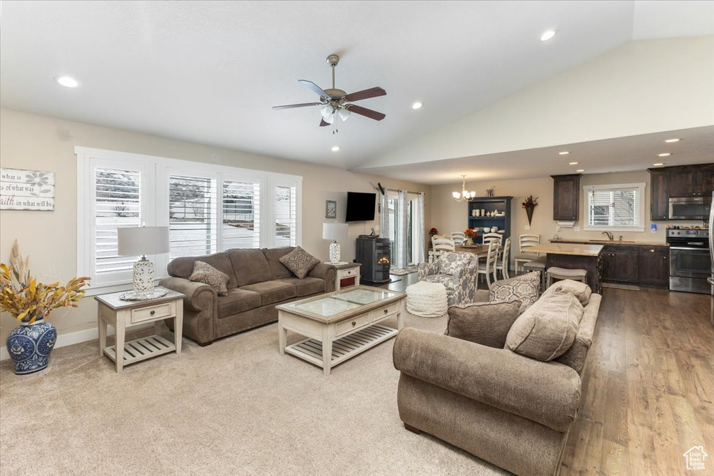 Living room with recessed lighting, plenty of natural light, ceiling fan with notable chandelier, and vaulted ceiling