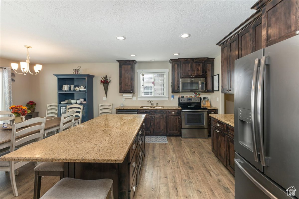 Kitchen featuring dark brown cabinetry, a chandelier, stainless steel appliances, and a sink