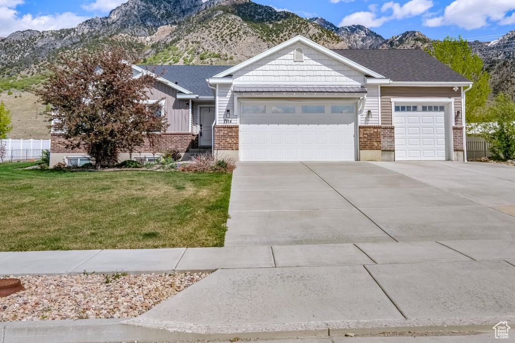 View of front of home featuring concrete driveway, an attached garage, brick siding, and a front yard