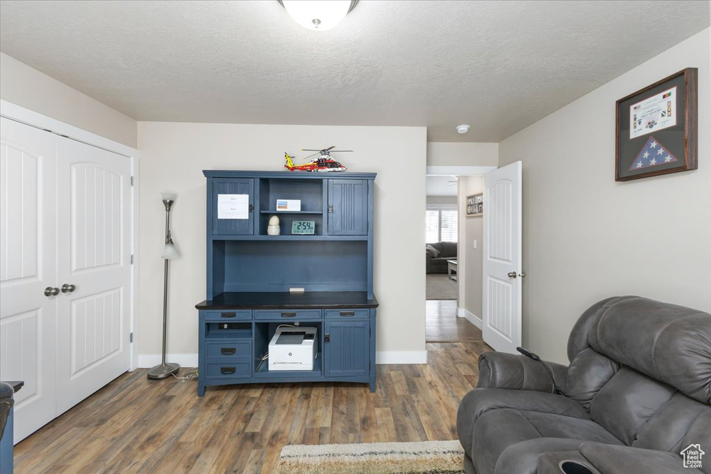 Living area featuring baseboards, dark wood-style flooring, and a textured ceiling