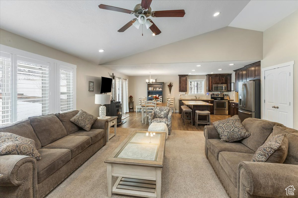 Living area featuring ceiling fan with notable chandelier, plenty of natural light, light wood-style floors, and recessed lighting