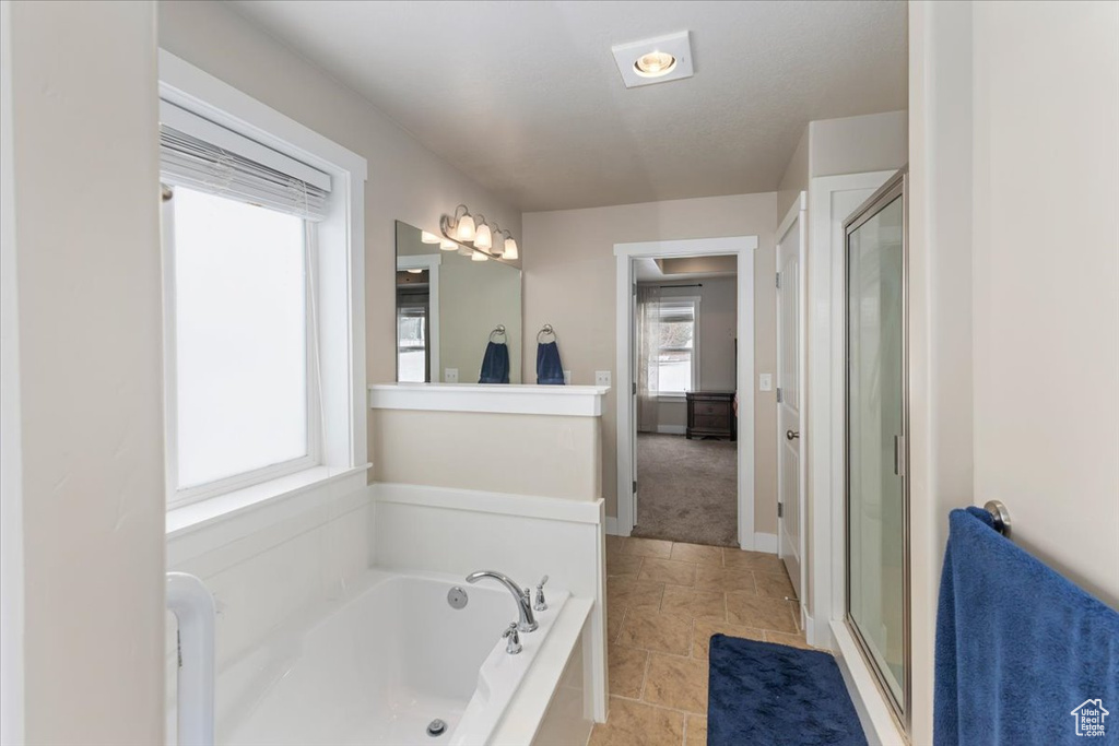 Full bath featuring tile patterned flooring, a stall shower, baseboards, and a garden tub