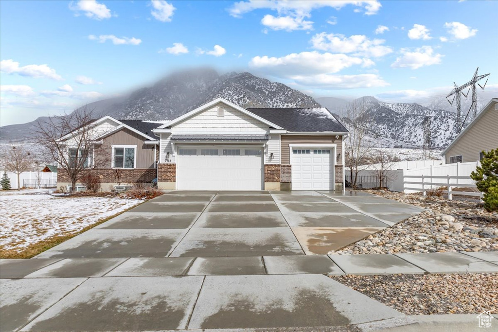 View of front of property with fence, brick siding, concrete driveway, a garage, and a mountain view