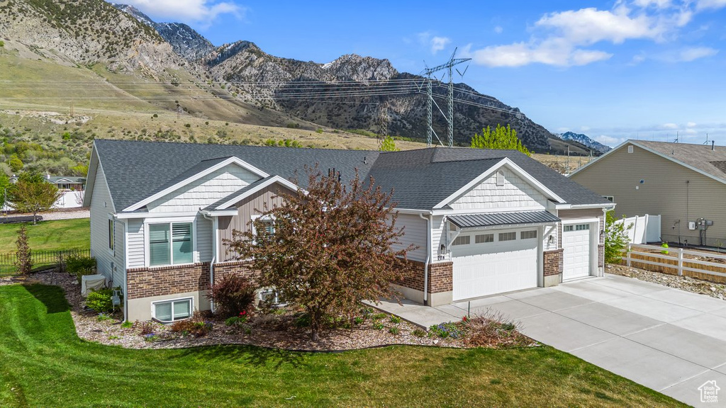 View of front of house with fence, an attached garage, driveway, a front yard, and a mountain view