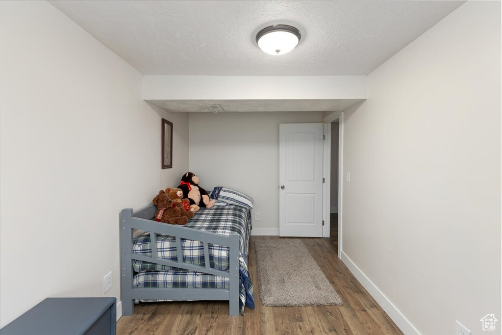 Bedroom with a textured ceiling, baseboards, and wood finished floors