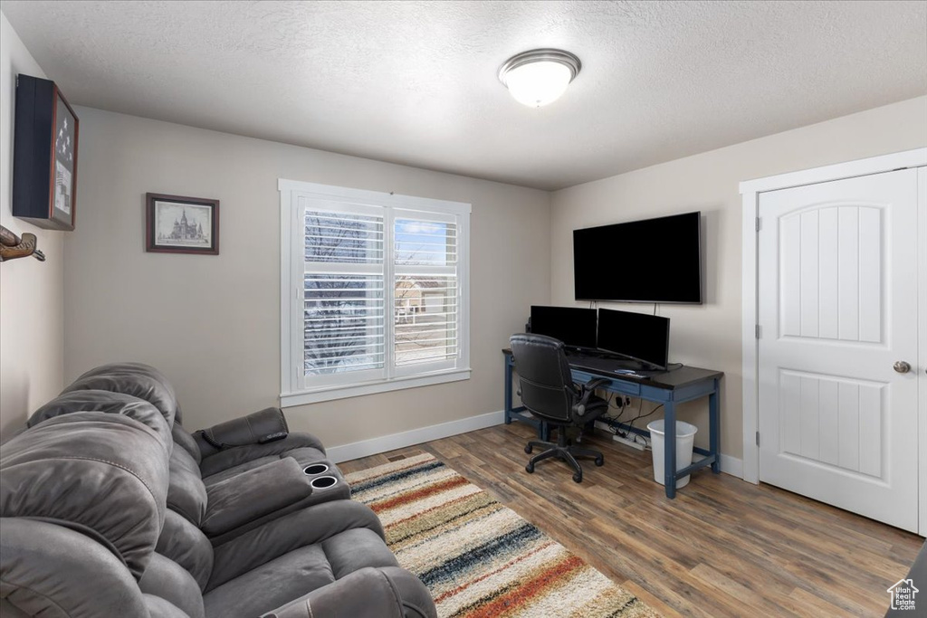 Home office featuring wood finished floors, baseboards, and a textured ceiling
