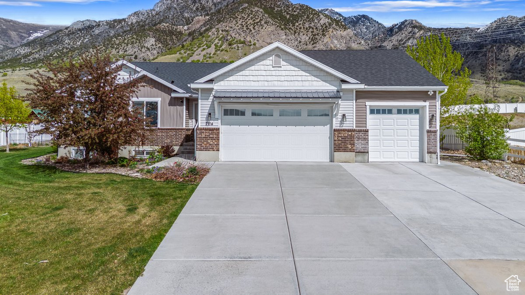 View of front facade with a garage, driveway, a mountain view, a front yard, and brick siding