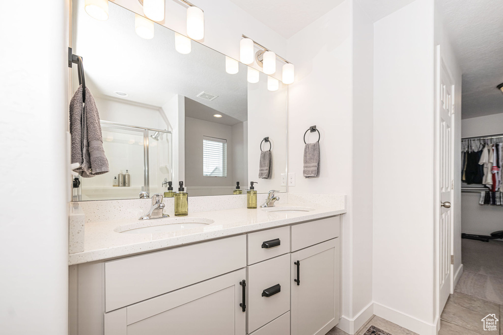 Bathroom featuring a sink, visible vents, a stall shower, and double vanity