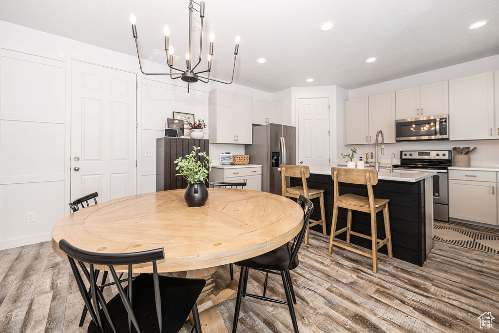 Dining space featuring an inviting chandelier, light wood-style flooring, and recessed lighting