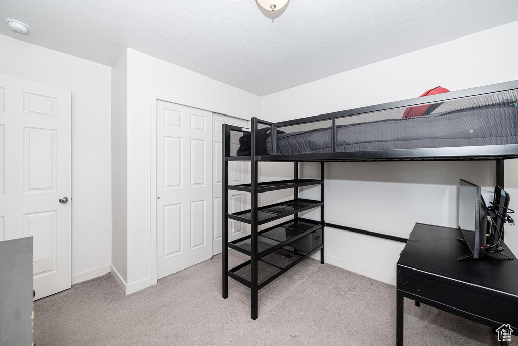 Bedroom with baseboards, light carpet, and a closet