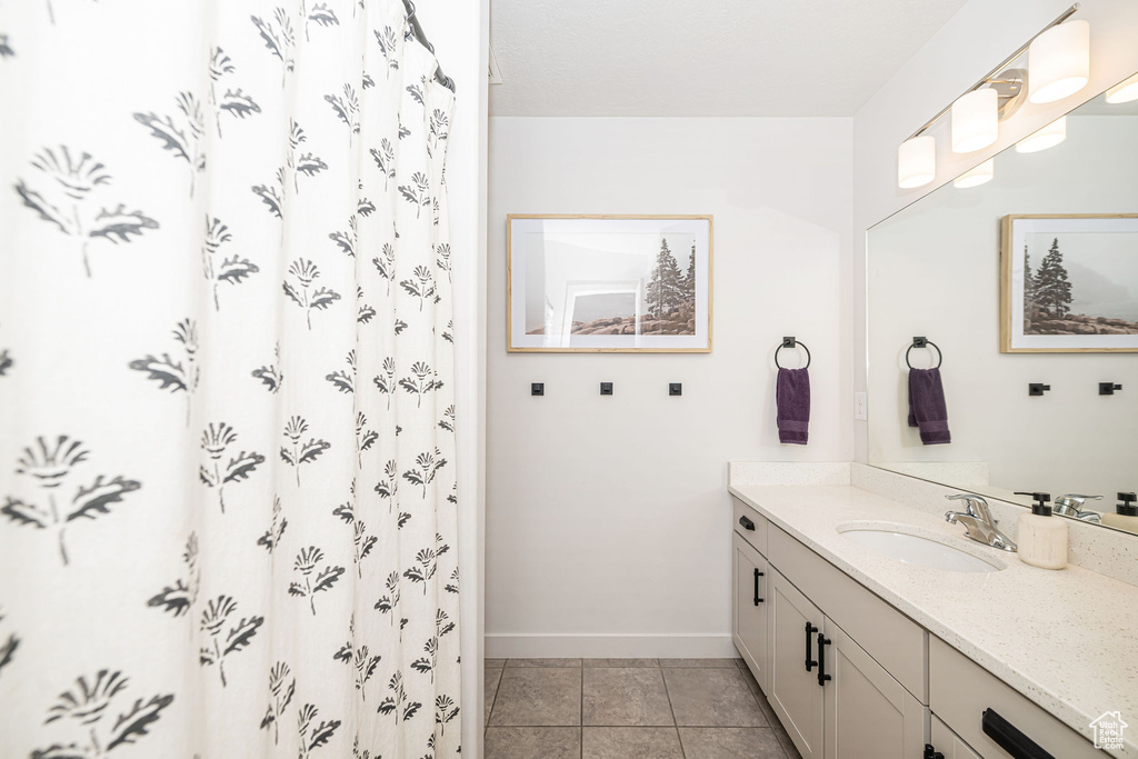 Bathroom featuring tile patterned flooring, vanity, and baseboards