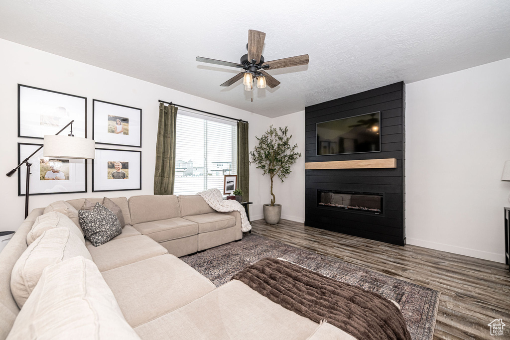 Living area featuring a fireplace, baseboards, a ceiling fan, and wood finished floors