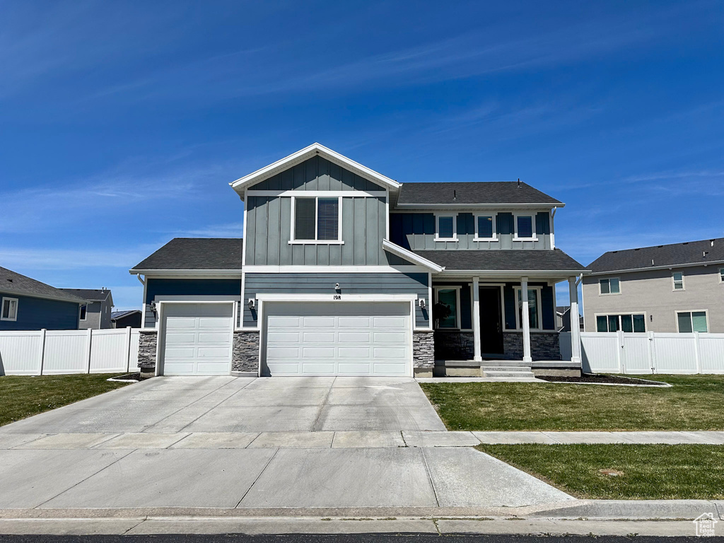 Craftsman inspired home with fence, stone siding, board and batten siding, and a front yard
