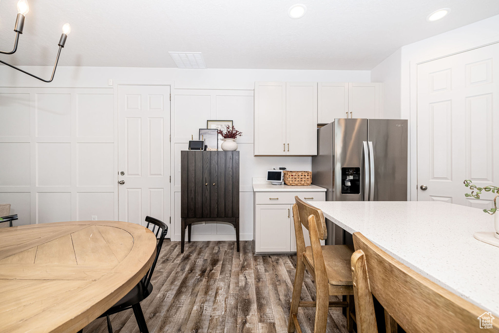 Kitchen featuring dark wood finished floors, recessed lighting, a kitchen breakfast bar, stainless steel refrigerator with ice dispenser, and white cabinets