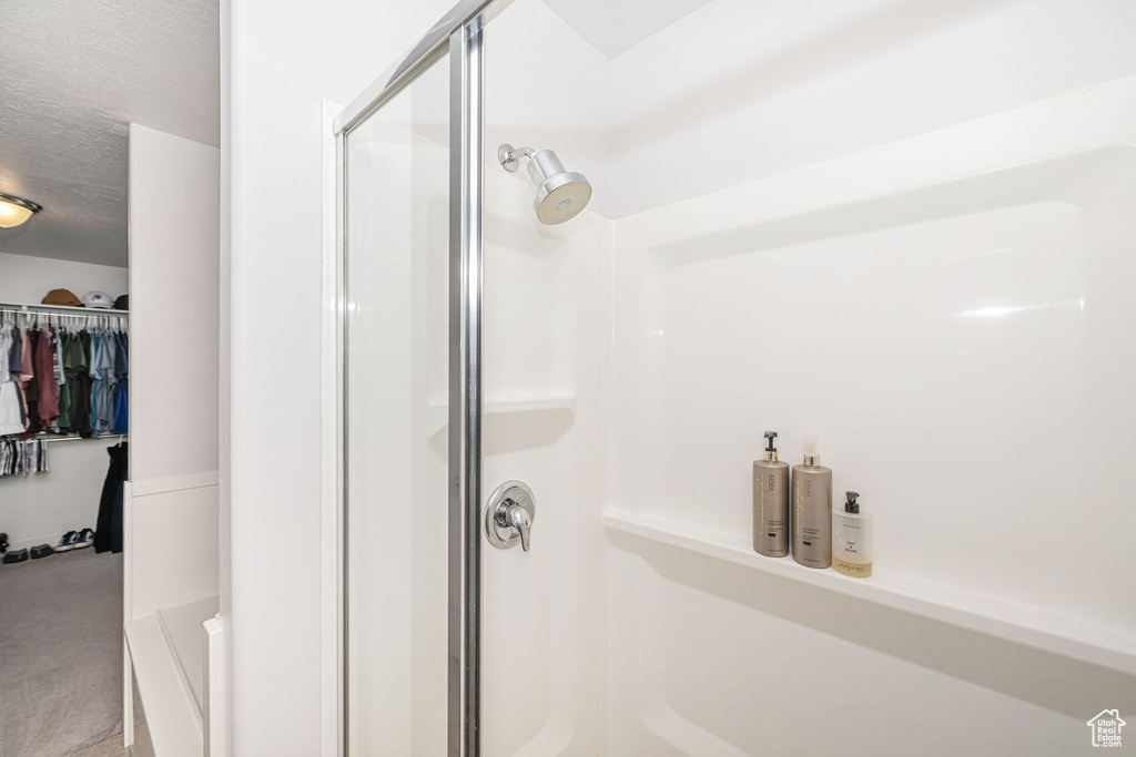 Bathroom featuring a spacious closet, a stall shower, and a textured ceiling