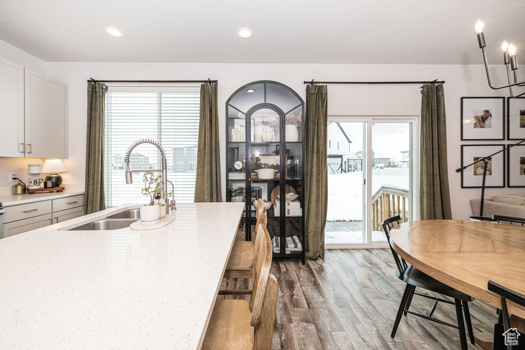 Kitchen with recessed lighting, white cabinetry, wood finished floors, and a sink