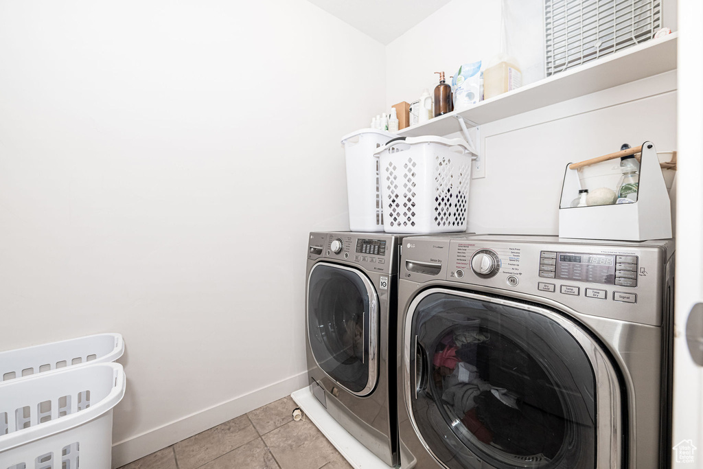 Washroom featuring light tile patterned floors, laundry area, washer and dryer, and baseboards