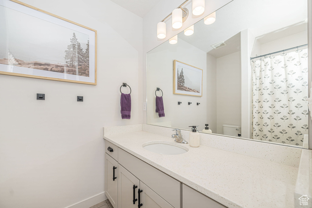 Bathroom with visible vents, toilet, curtained shower, baseboards, and vanity