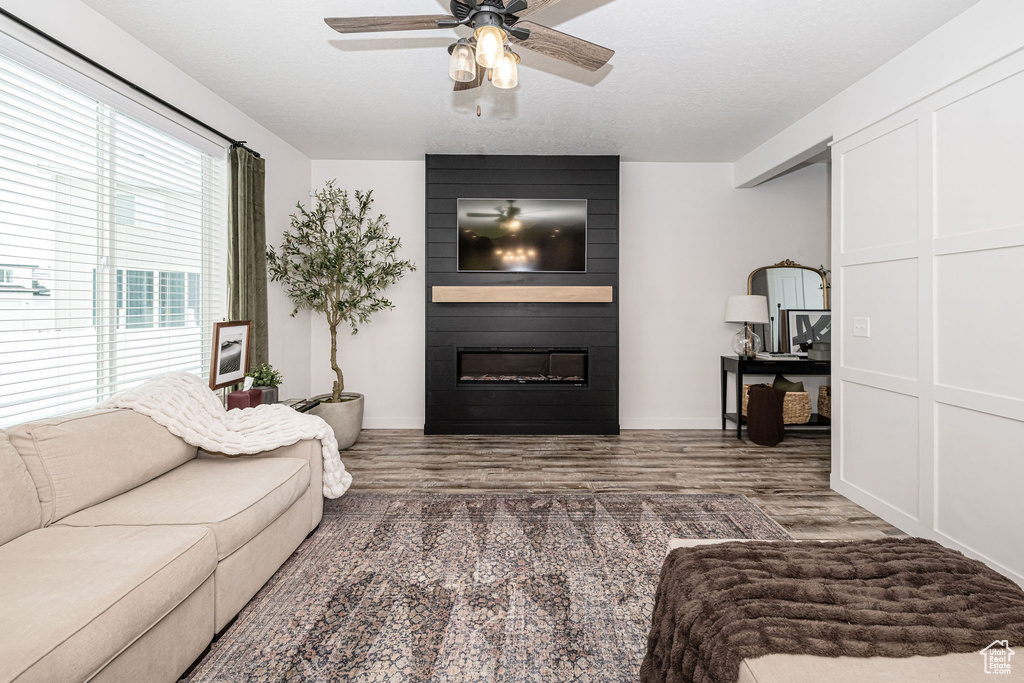 Living area featuring wood finished floors, a textured ceiling, ceiling fan, and a fireplace