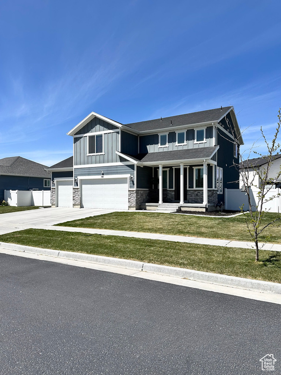 View of front of property featuring stone siding, an attached garage, covered porch, and board and batten siding