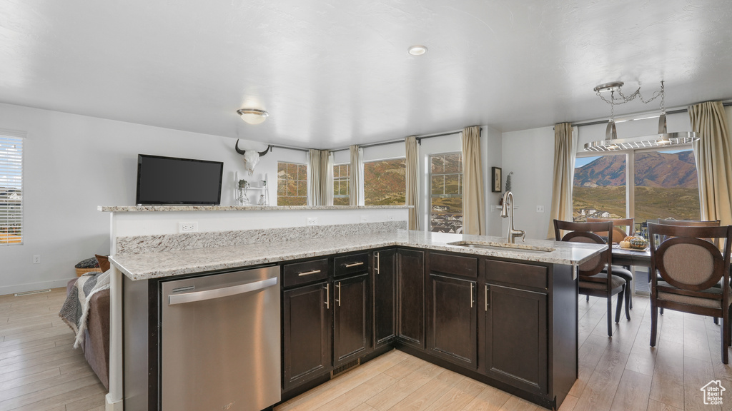 Kitchen with a sink, light wood-type flooring, light stone counters, and stainless steel dishwasher