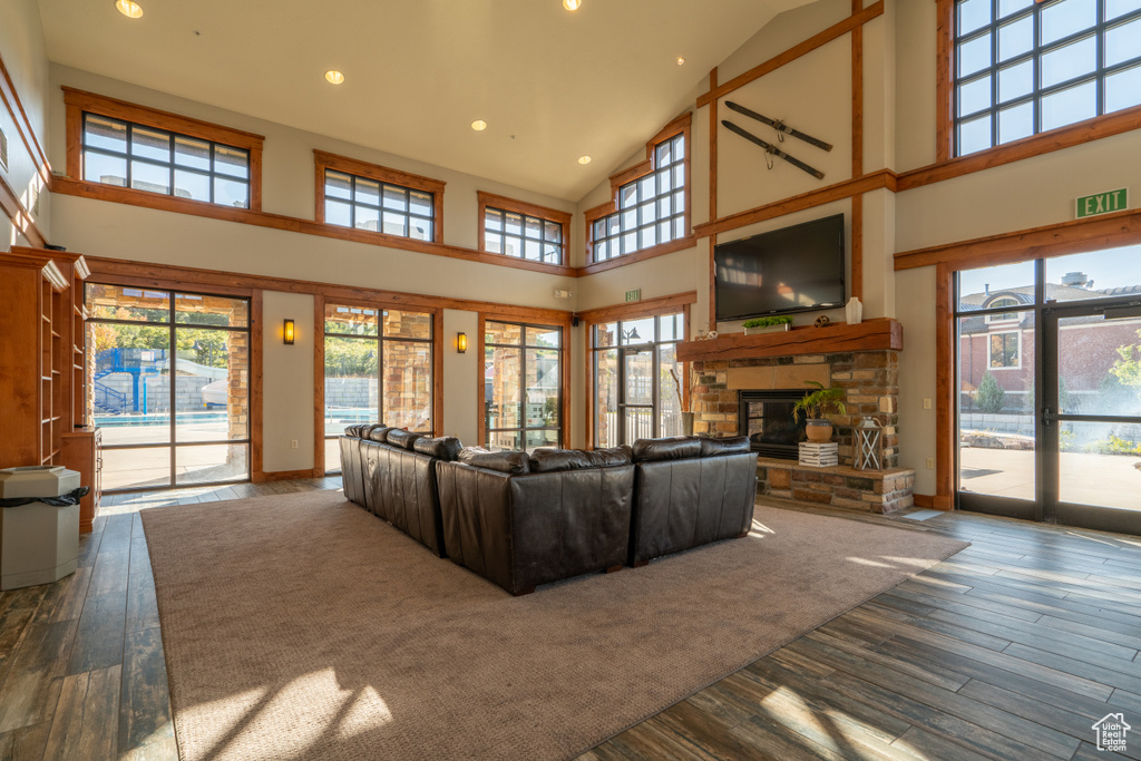 Living area featuring baseboards, wood-type flooring, high vaulted ceiling, and a stone fireplace