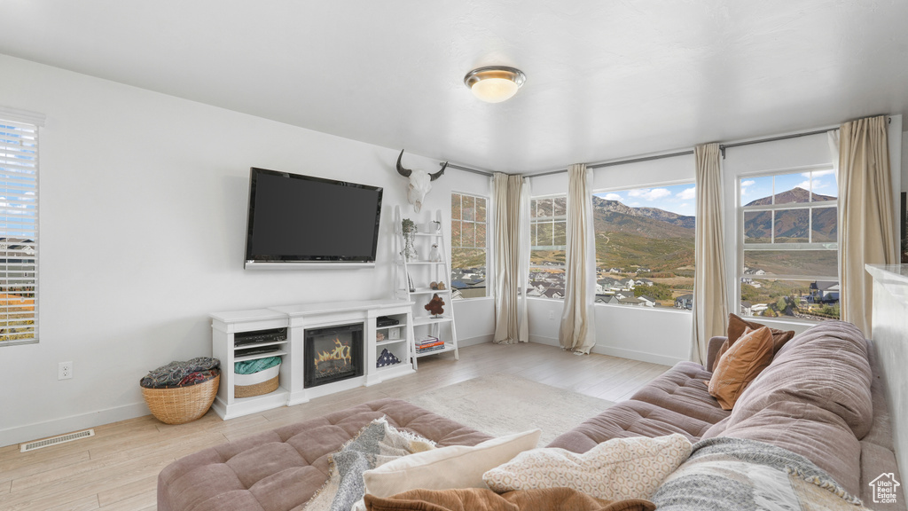Living room with a wealth of natural light, visible vents, baseboards, and wood finished floors