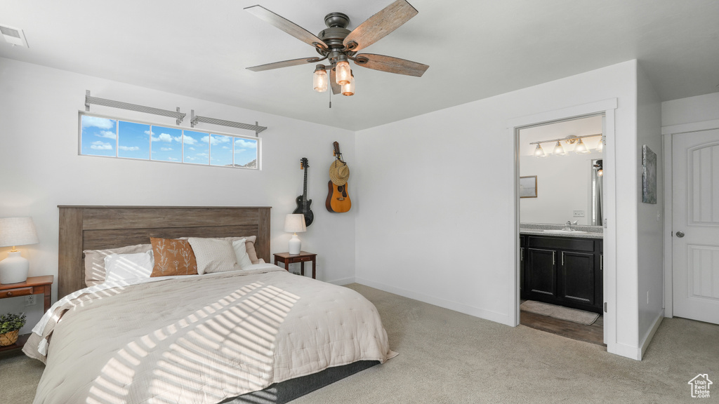 Bedroom with ensuite bath, baseboards, and light carpet