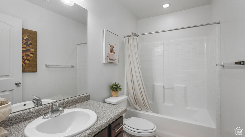Bathroom featuring shower / bathtub combination with curtain, toilet, and vanity
