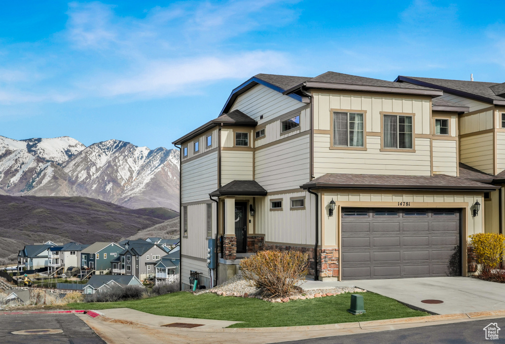 Townhome / multi-family property with board and batten siding, stone siding, an attached garage, a mountain view, and driveway