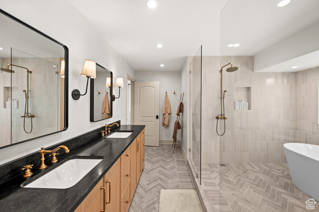 Bathroom with a tile shower, recessed lighting, and a sink