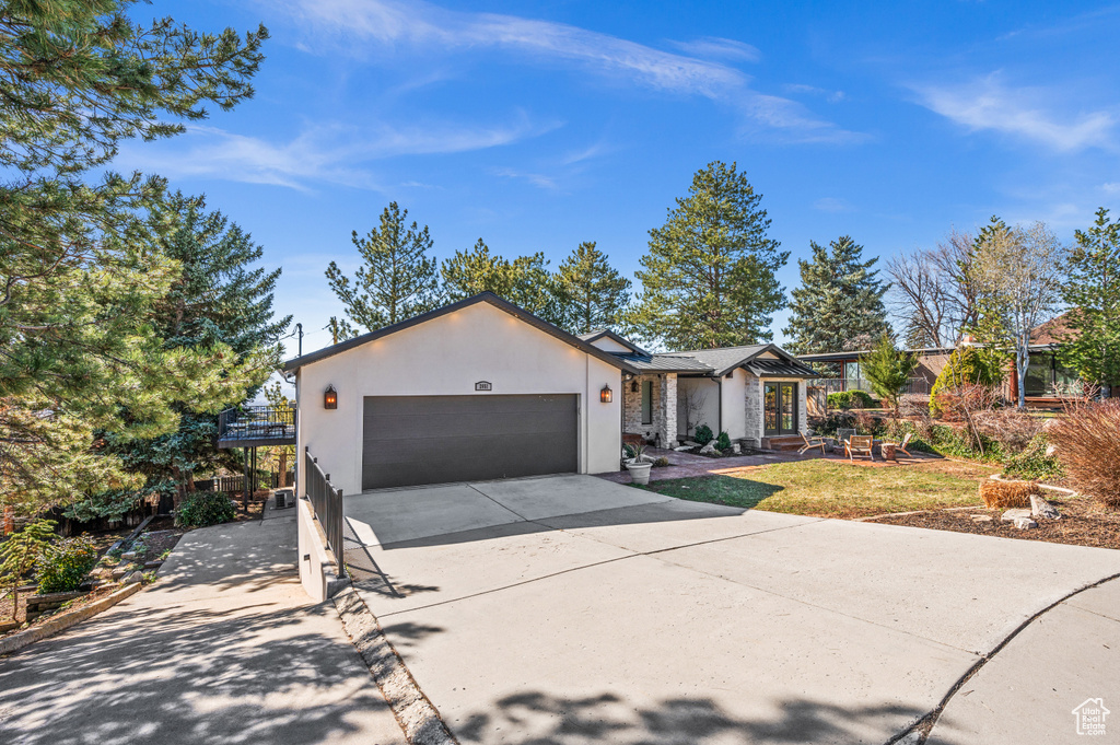 View of front facade featuring an attached garage, driveway, and stucco siding