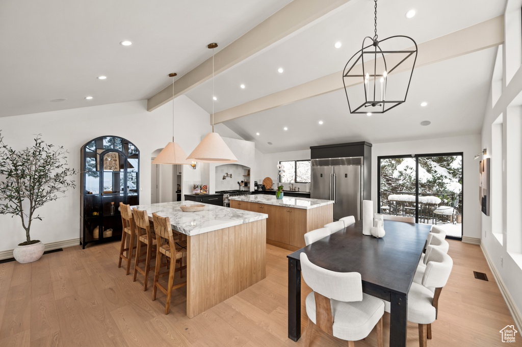 Dining space with lofted ceiling with beams, a notable chandelier, baseboards, and light wood-type flooring