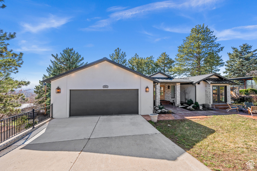View of front of property featuring stucco siding, french doors, metal roof, driveway, and a standing seam roof