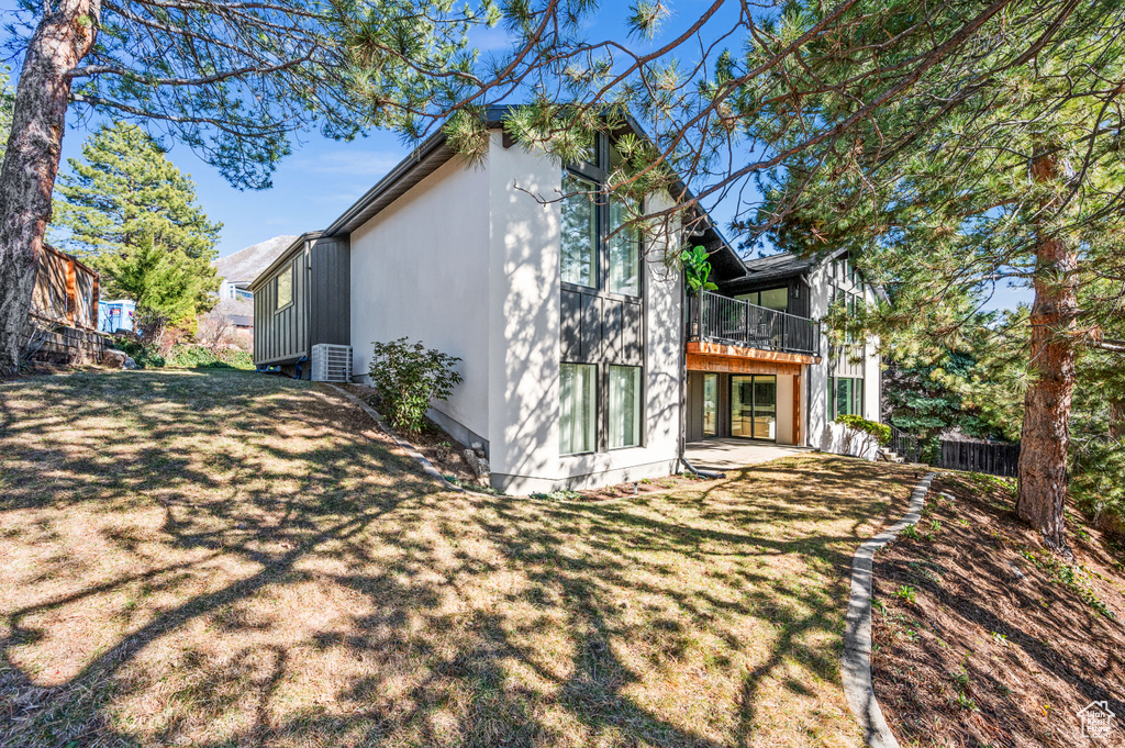 Rear view of house featuring a patio area, a lawn, fence, and central AC
