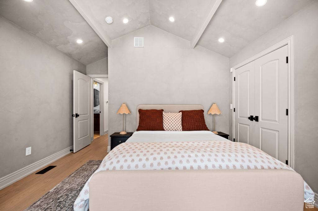 Bedroom with visible vents, baseboards, vaulted ceiling, and light wood finished floors