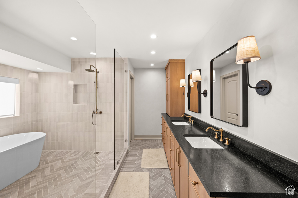 Full bath with a tile shower, recessed lighting, double vanity, and a sink