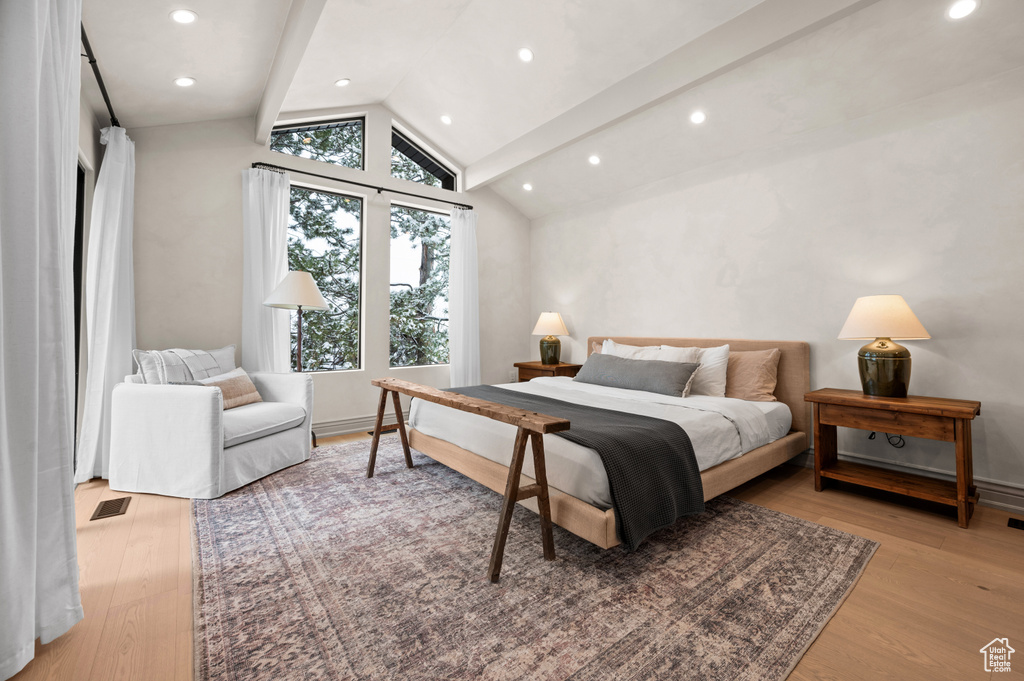Bedroom with vaulted ceiling, wood finished floors, visible vents, and baseboards