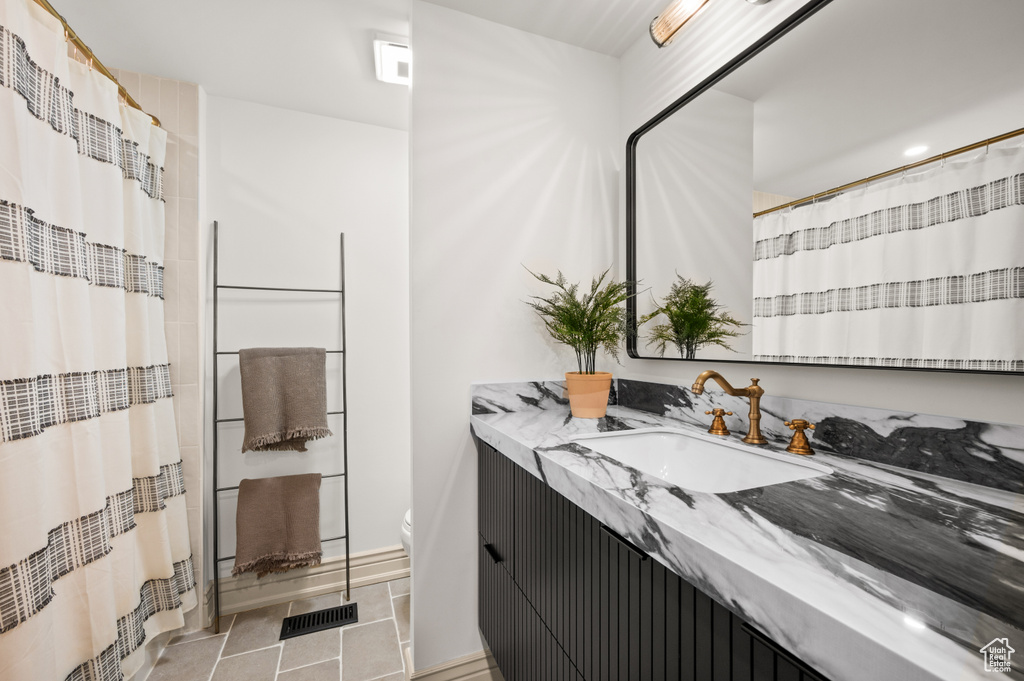 Bathroom featuring vanity, a shower with shower curtain, visible vents, tile patterned flooring, and toilet