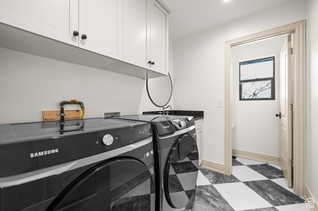 Clothes washing area with baseboards, cabinet space, a sink, tile patterned floors, and washing machine and dryer