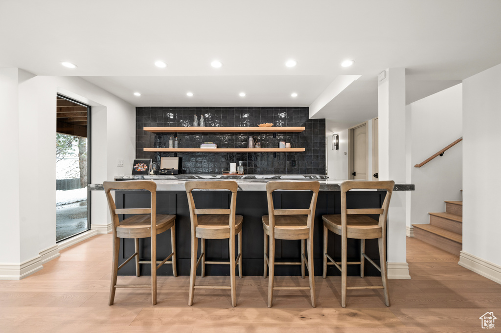 Bar with light wood-style flooring, decorative backsplash, recessed lighting, stairway, and indoor wet bar