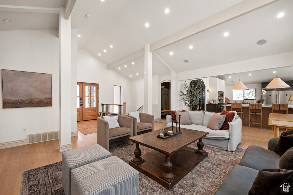 Living room with visible vents, high vaulted ceiling, recessed lighting, arched walkways, and light wood-style floors
